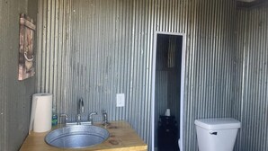 Ein Badezimmer mit Holzwaschtisch, Waschbecken, Toilette und Spiegel.
