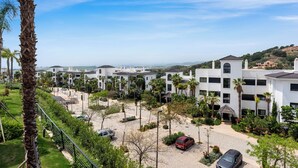 A residential area with white buildings, palm trees, and a clear sky.