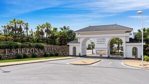A gated entrance with a stone wall and the name "ESTEPONA HILLS" prominently displayed.