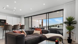 A modern living room with a sectional sofa, a coffee table, and a view of the outside.