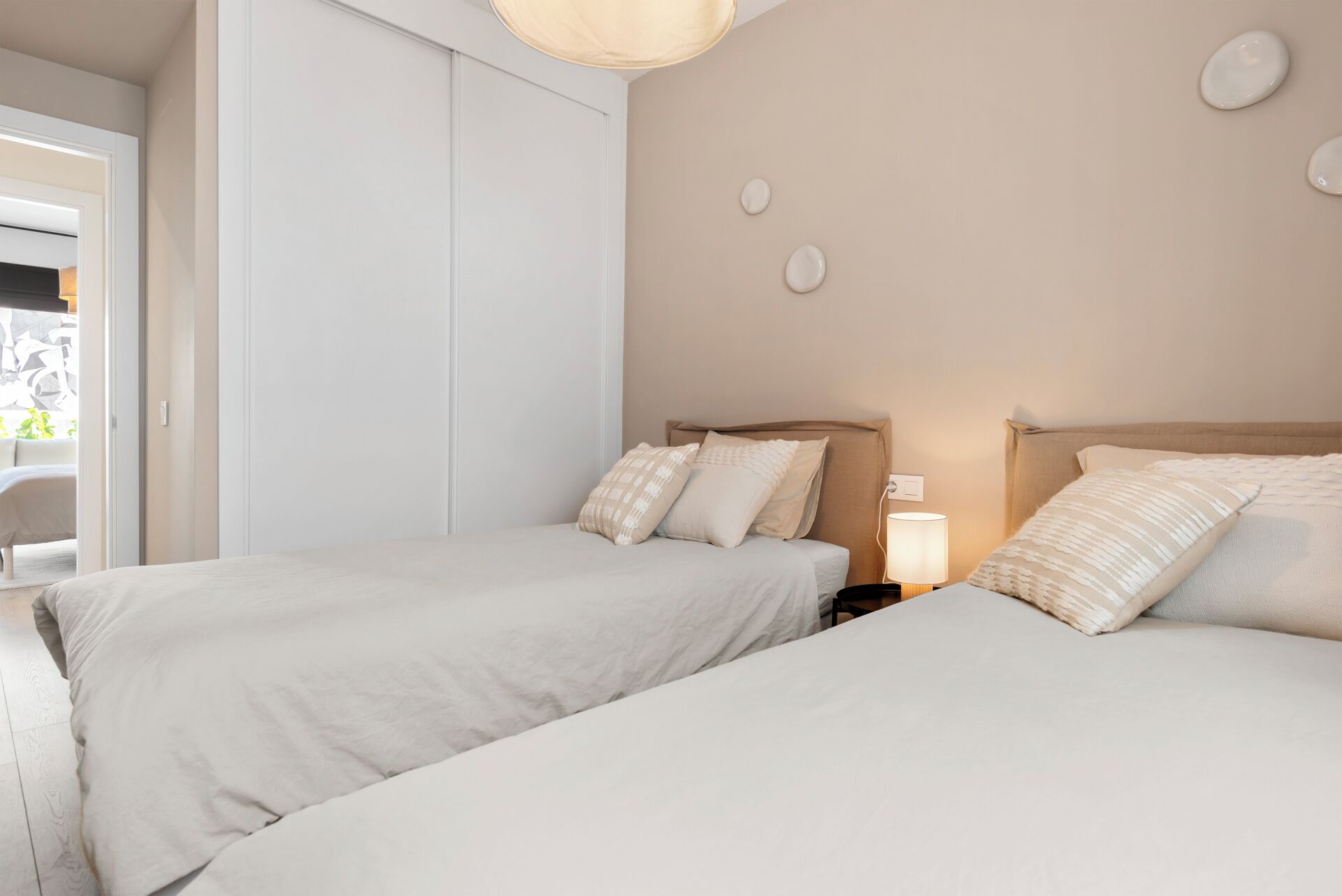 A hotel room with two beds, a wardrobe, and a bedside lamp.