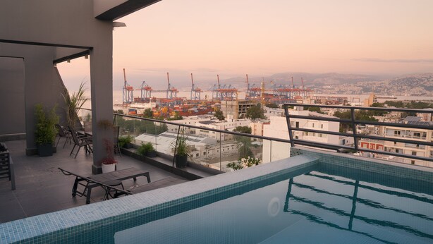 A rooftop pool with a view of a port and cityscape. - Unit for Living (Beirut)