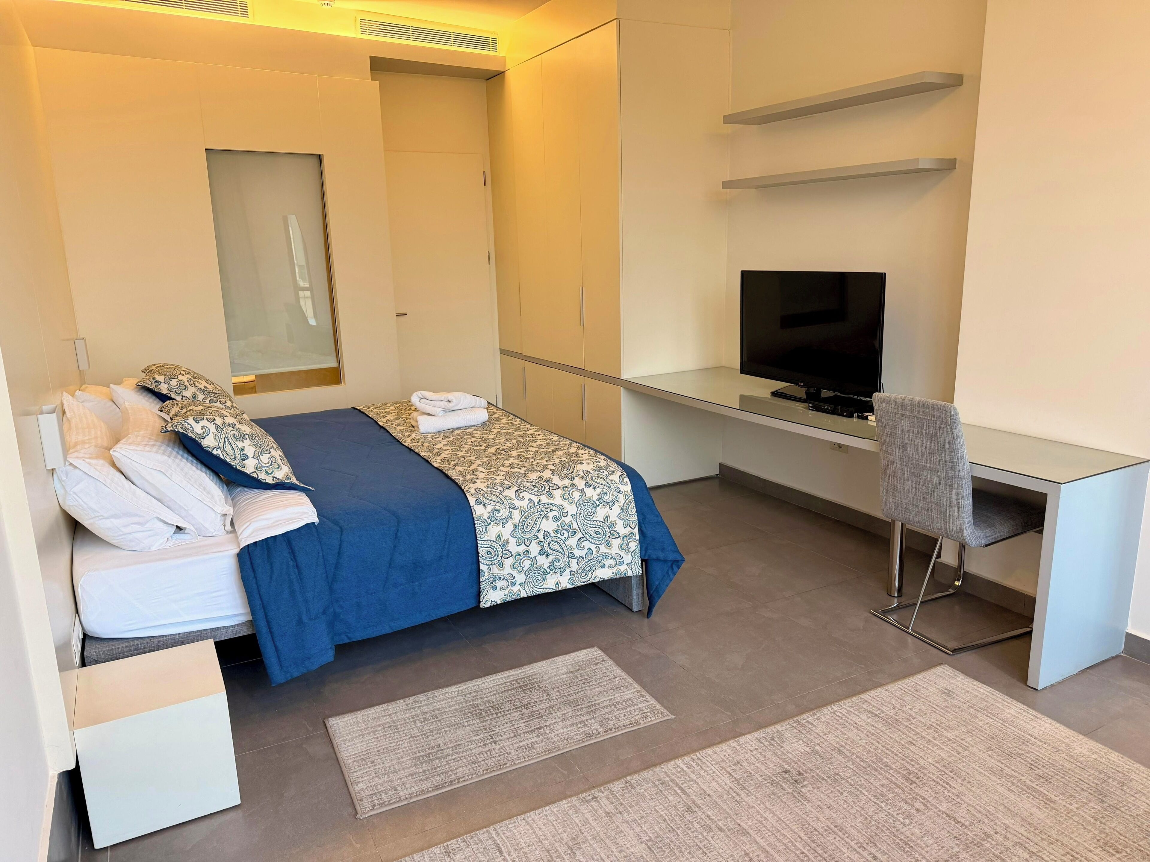 A hotel room with a bed, a desk, a television, and a chair.