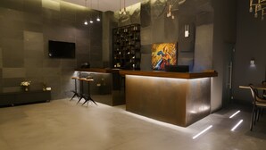 A modern reception area with a wooden counter, a TV mounted on the wall, and a bookshelf. - Unit for Living (Beirut)