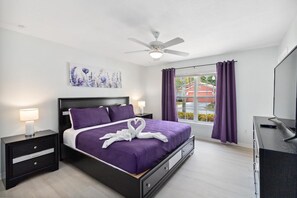 A modern bedroom with a bed, nightstands, a ceiling fan, a TV, and a window with curtains. - Great Community, amazing private pool, near Disney! (Davenport)