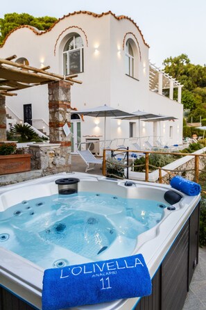 A hot tub with a blue towel labeled "L'Olivella Anacapri 11" in front of a white building with arched windows and outdoor seating. - Villa Olivella in Anacapri (Anacapri)