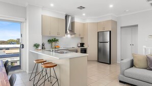A modern kitchen with a central island, stainless steel appliances, and a view of solar panels outside.