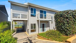 A two-story building with a balcony, a gated entrance, and a well-maintained garden with various plants.