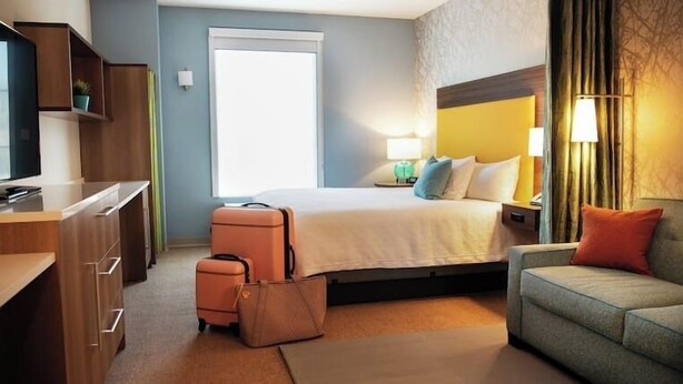 A hotel room with a bed, a desk, a chair, a suitcase, and a lamp. - Home2 Suites By Hilton American Canyon Napa Valley (American Canyon)