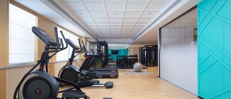 Une salle de sport équipée de tapis de course, de vélos elliptiques et de poids libres.