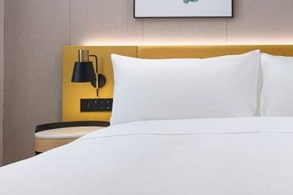 Une chambre d’hôtel avec un lit, deux tables de chevet et des lampes fixées au mur.