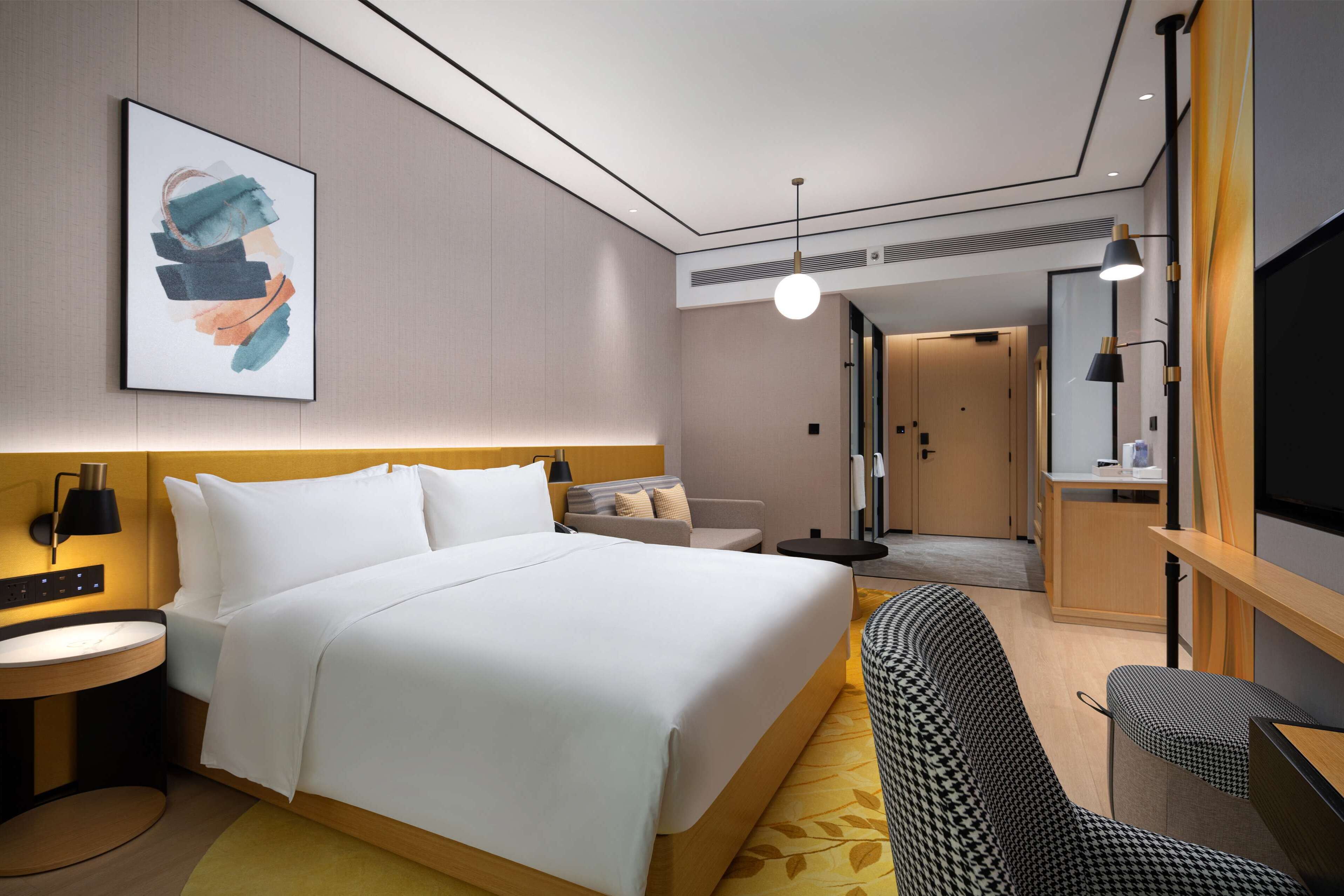 Une chambre d’hôtel moderne équipée d’un grand lit, d’un canapé, d’un bureau et d’une télévision.