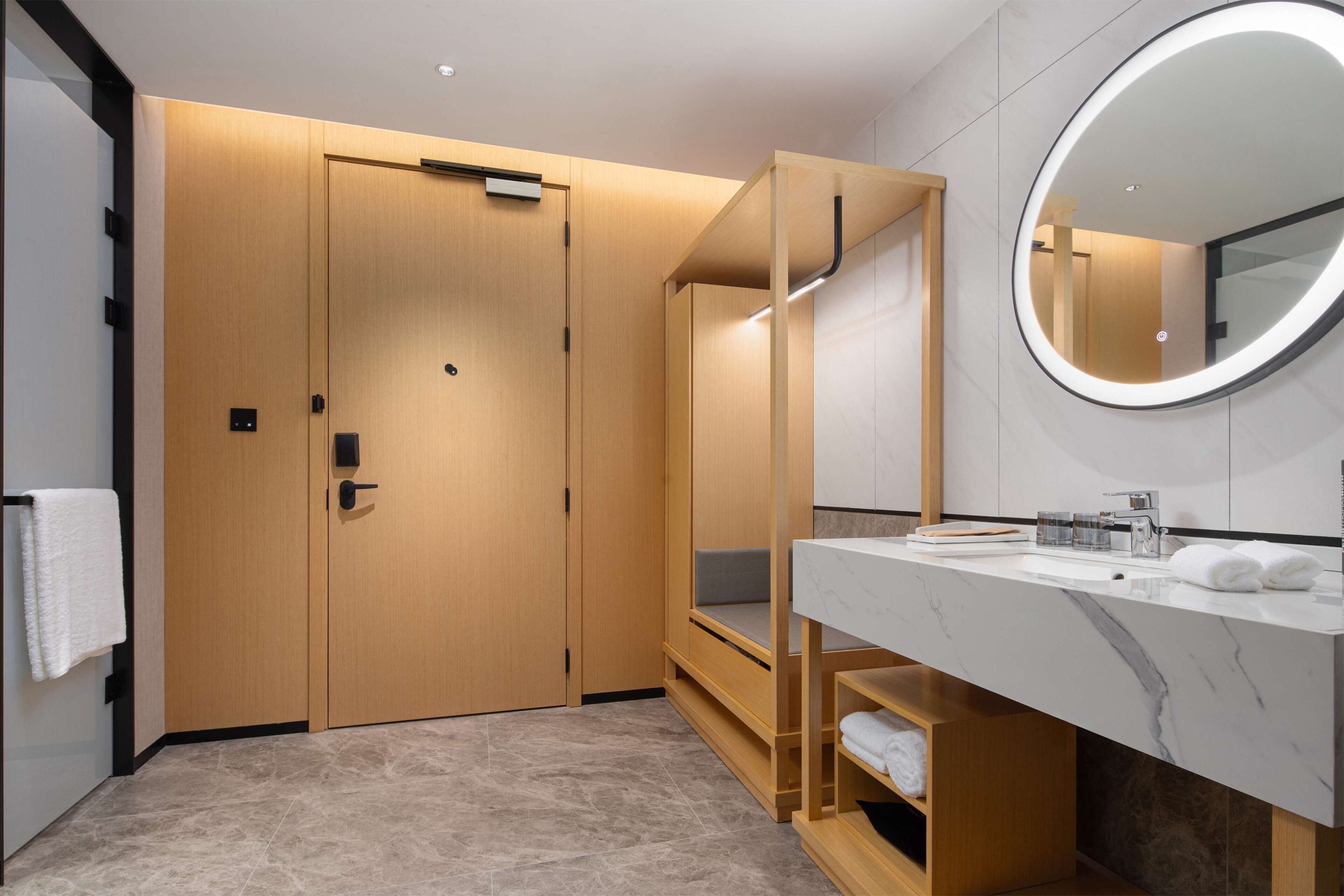 Un baño moderno con tocador de madera, un espejo grande y un banco empotrado.