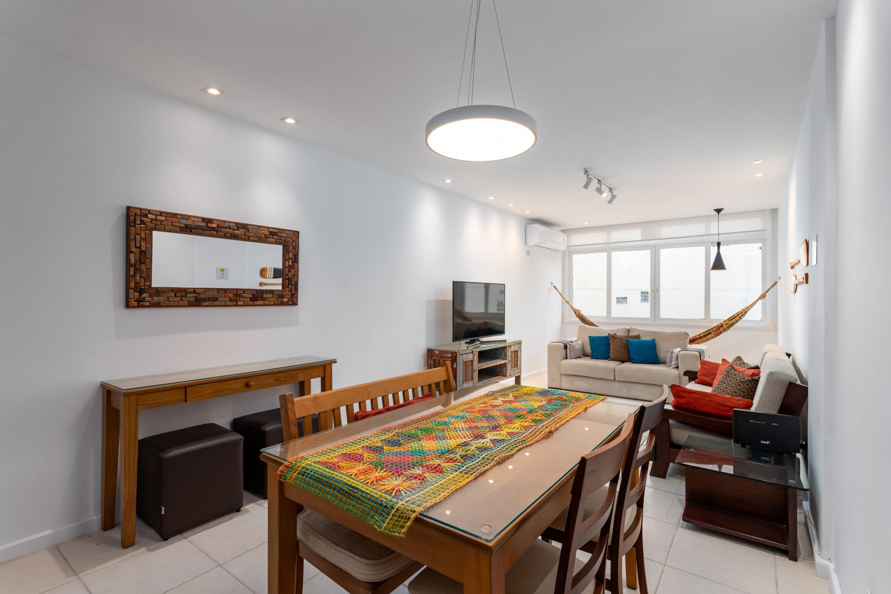 A modern living room with a dining area, a TV, and a large window.