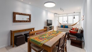 A modern living room with a dining area, a TV, and a large window. - For Families 10min From Copacabana Beach Pl804 (Rio de Janeiro)