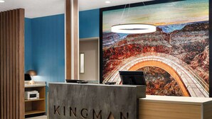 Uma receção com o nome "KINGMAN" na área de lobby, apresentando uma grande pintura de um cânion e um candeeiro pendente.