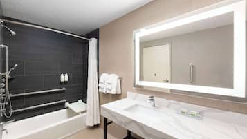 Un baño moderno con bañera, un espejo grande y tocador con encimera de mármol.