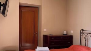 Ein Schlafzimmer mit einem Bett, einer Holztür, einem Schminktisch und einem kleinen Hocker.
