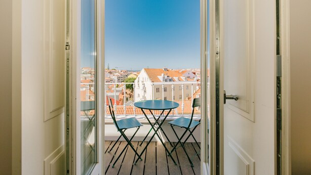 Un balcon avec une table et des chaises, d’où l’on peut admirer la vue sur la ville.