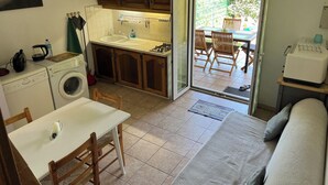 Een kleine keuken met een eethoek, een wasmachine en een bank.