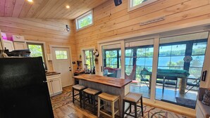 Une cuisine avec des murs en bois, un réfrigérateur noir et un îlot central en bois avec des tabourets.