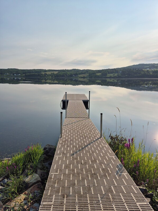 A wooden dock extending into calm water with a clear view of distant hills. - The Riverside Inn - a welcoming, peaceful retreat on the water. (Lower Woodstock)