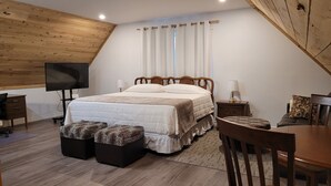 A bedroom with a bed, a TV, a desk, and a chair.