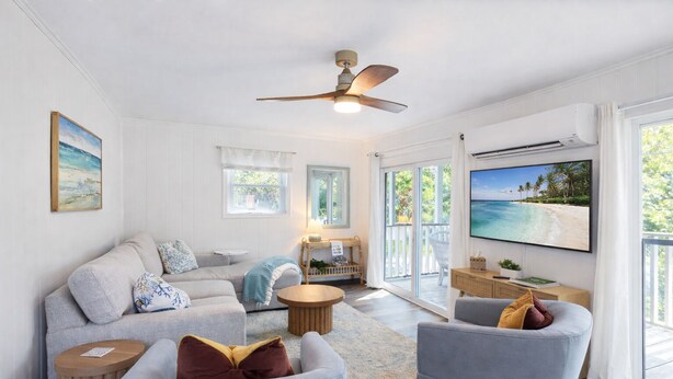 A spacious living room with a large TV, comfortable seating, and a balcony with a view. - Walk to the Beach! Firepit, games, pets welcome, bring your boat! (Edisto Island)