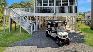 A two-story building with a covered area and a golf cart parked in front. - Walk to the Beach! Firepit, games, pets welcome, bring your boat! (Edisto Island)