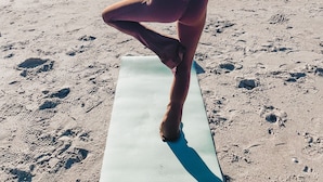 A person performing a yoga pose on a mat at the beach with the ocean in the background. - Walk to the Beach! Firepit, games, pets welcome, bring your boat! (Edisto Island)