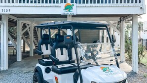 A golf cart parked in front of a building with a balcony and a sign reading "SEASCAPE". - Walk to the Beach! Firepit, games, pets welcome, bring your boat! (Edisto Island)