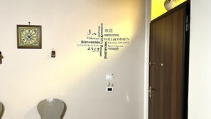 Una pared con mensajes de bienvenida en varios idiomas y un reloj enmarcado.