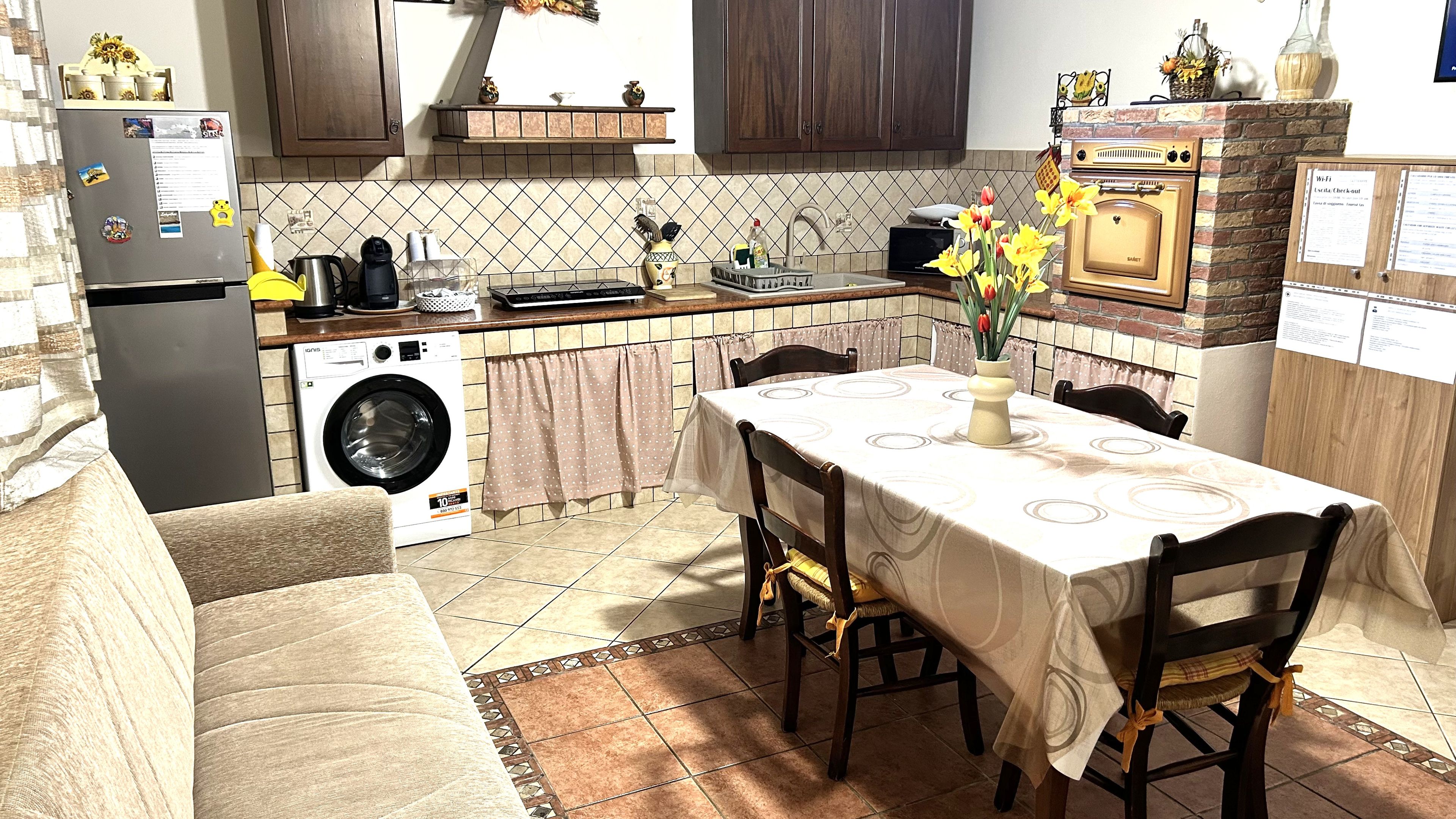 Een kleine keuken met een eethoek, een wasmachine en een tafel gedekt voor vier personen.