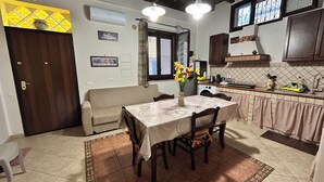 A compact kitchen with a dining table, a sofa, and a washing machine.