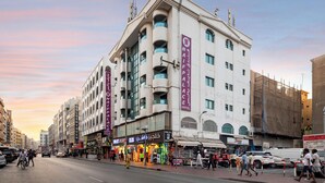 A multi-story hotel with balconies, a ground floor with shops, and a sign for the "Naiif Palace Hotel".