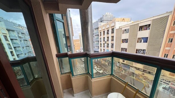A balcony with a glass railing, a small table, and a view of the cityscape.