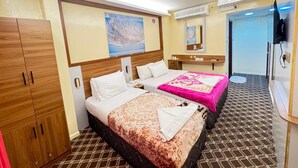 A hotel room with two beds, a wardrobe, a bathroom, and a television.