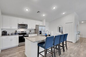 A modern kitchen with white cabinets, stainless steel appliances, and a granite countertop.