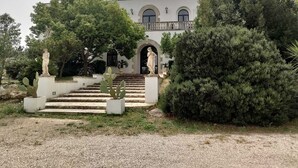 Un bâtiment à la façade symétrique, doté d’une entrée centrale surmontée d’un arc et d’une statue au sommet de l’escalier.