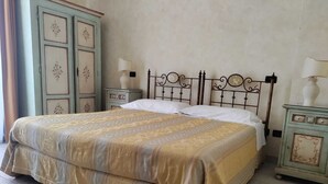 Un lit avec une couvre-lit à motifs, une tête de lit en métal et deux tables de chevet avec des lampes.