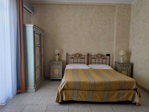A bedroom with a bed, two nightstands, a wardrobe, and a window with curtains.