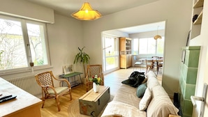 Ein großzügiges Wohnzimmer mit einer Couch, Sesseln, einem Couchtisch und einem Essbereich mit Tisch und Stühlen.