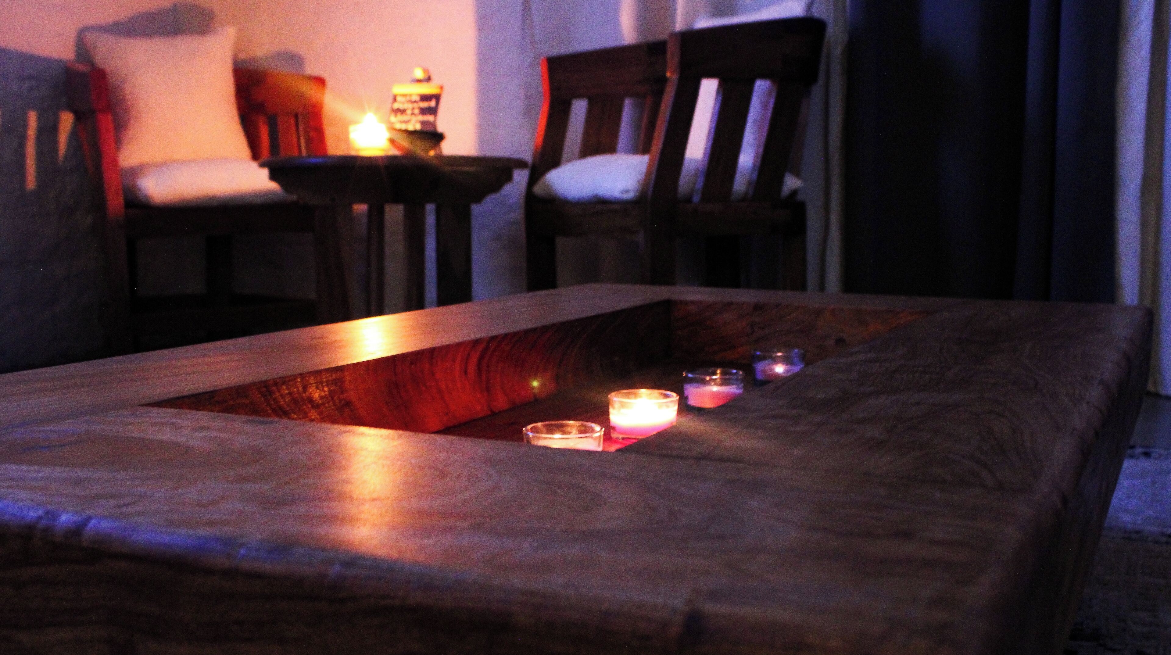 Una mesa de centro de madera con velas y una lámpara de mesa pequeña.