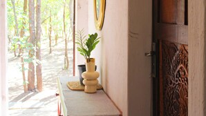 A wooden door with intricate carvings, a small table with a potted plant, and a mirror on the wall. - 3 Bedroom House Sleeps 6, Mini Bar, Free Parking (Livingstone)