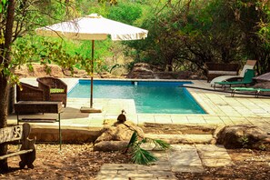 A swimming pool with lounge chairs and a shaded area. - 3 Bedroom House Sleeps 6, Mini Bar, Free Parking (Livingstone)