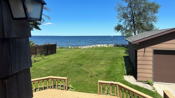 A wooden deck with a view of the sea, a grassy yard, and a small shed. - Large Waterfront Lake Michigan - Book Fall Colors! (Menominee)