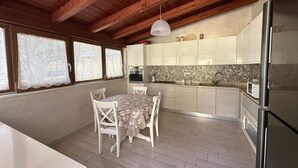 A modern kitchen with wooden beams, a dining table with chairs, and a refrigerator.