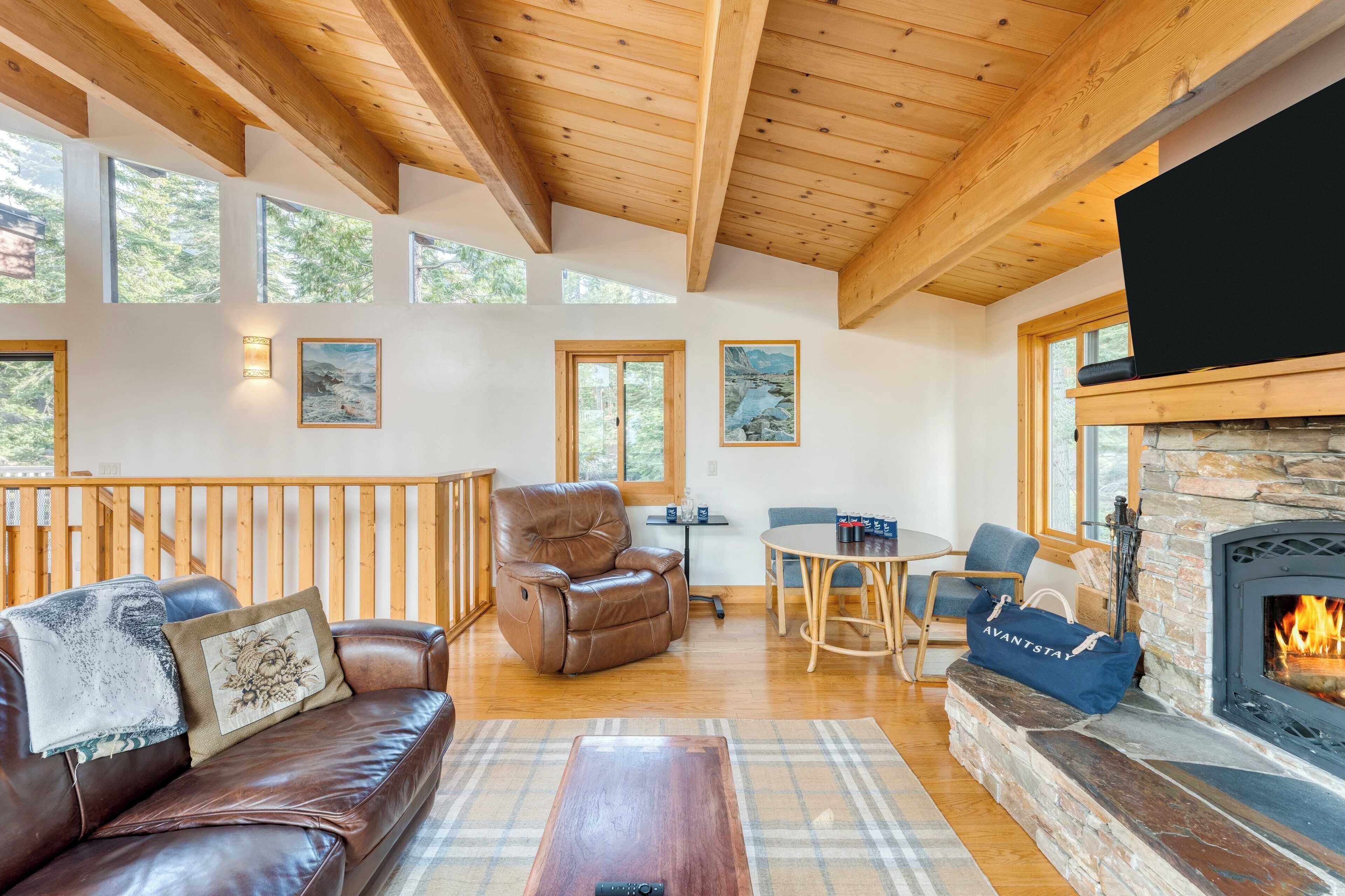 A spacious living room with a fireplace, leather sofa, and wooden ceiling beams.
