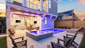 A modern two-story house with a swimming pool, outdoor seating, and a covered patio area.