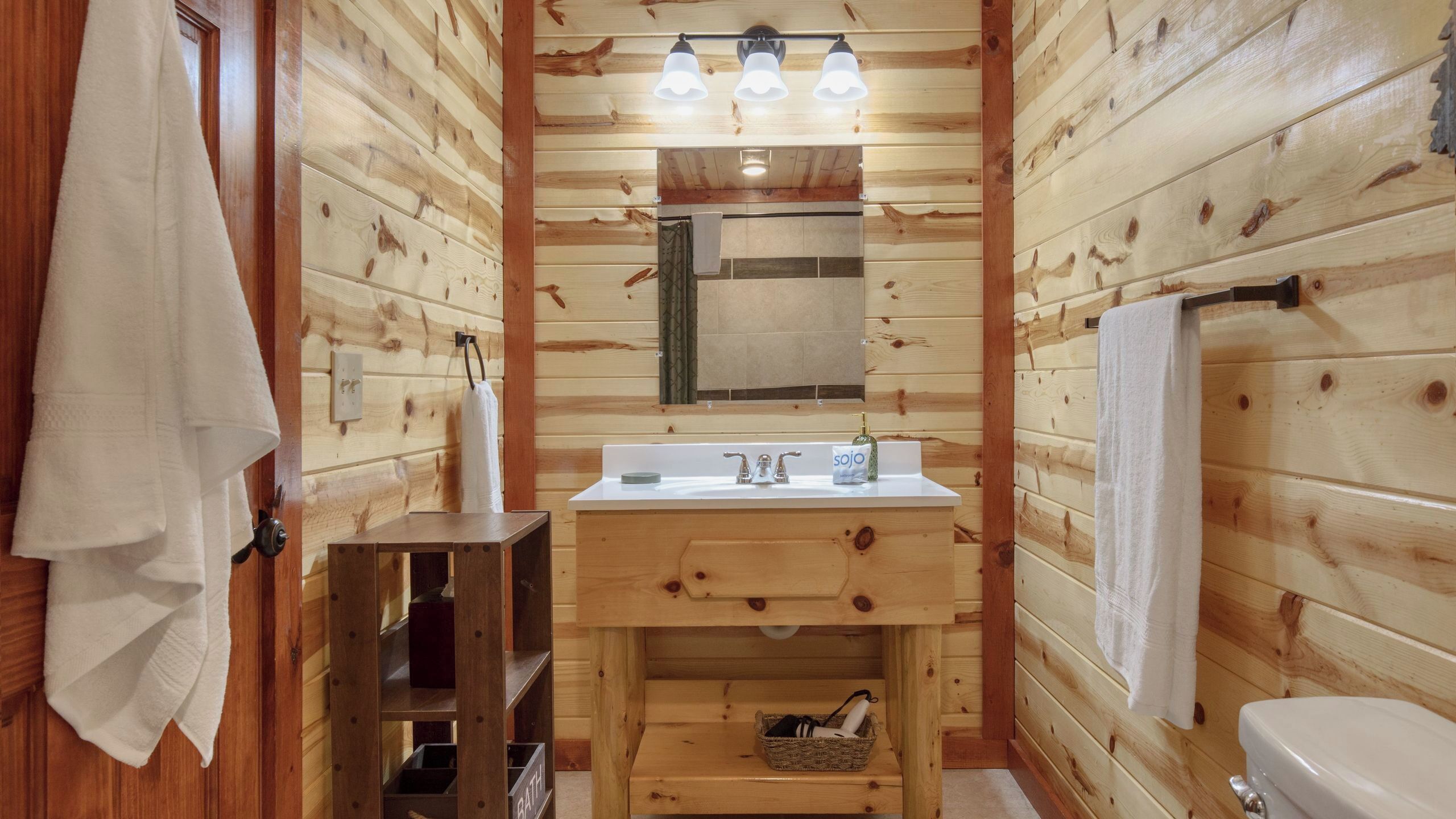 Ein Badezimmer einer Holzhütte mit Waschbecken, Spiegel und Handtuchhalter.
